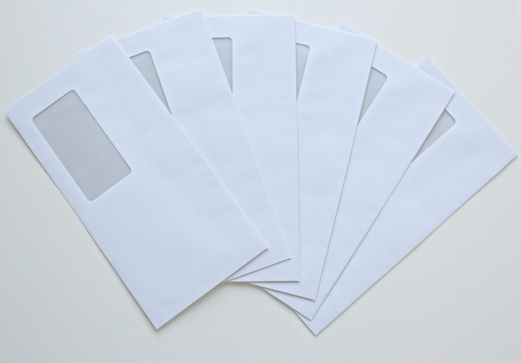 A set of white window envelopes fanned out on a flat surface, ready for mailing or office use.